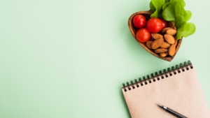 Notebook and heart-shaped plate with lettuce, cherry tomatoes, and almonds.